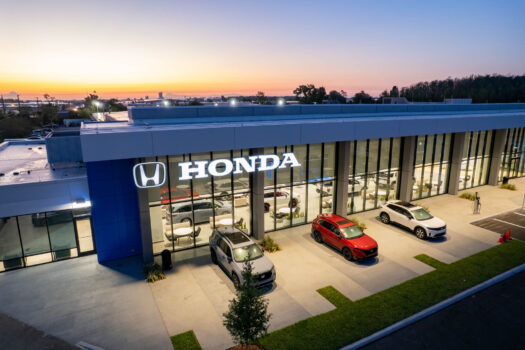 Exterior evening view of the Coggin Honda of Orlando dealership featuring the illuminated glass showroom and parking lot.