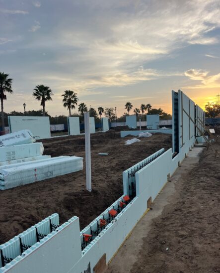 Construction progress showing the four-story main building structure with the blue ICF walls visible.
